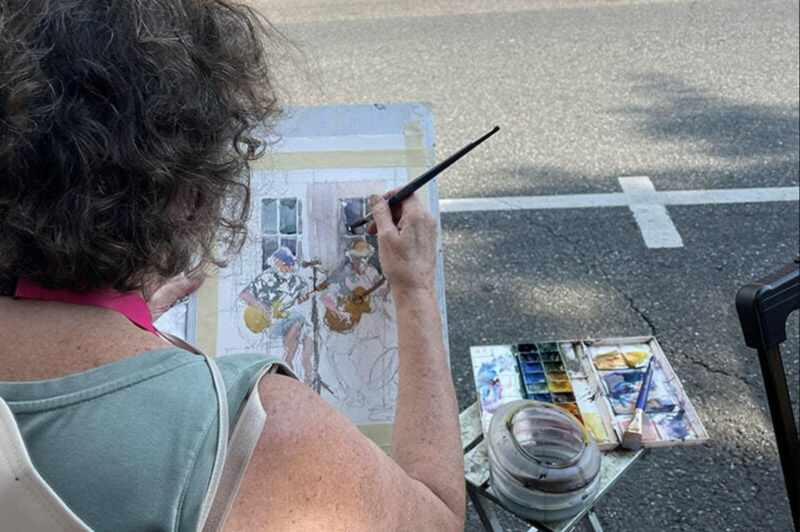 Artist Marilyn Rose painting a watercolor on the street